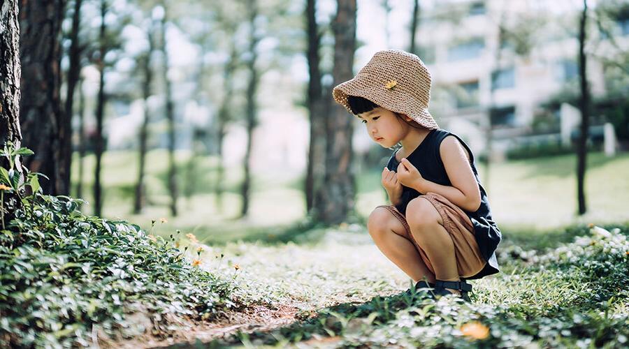 Little girl crouching in forest looking at nature